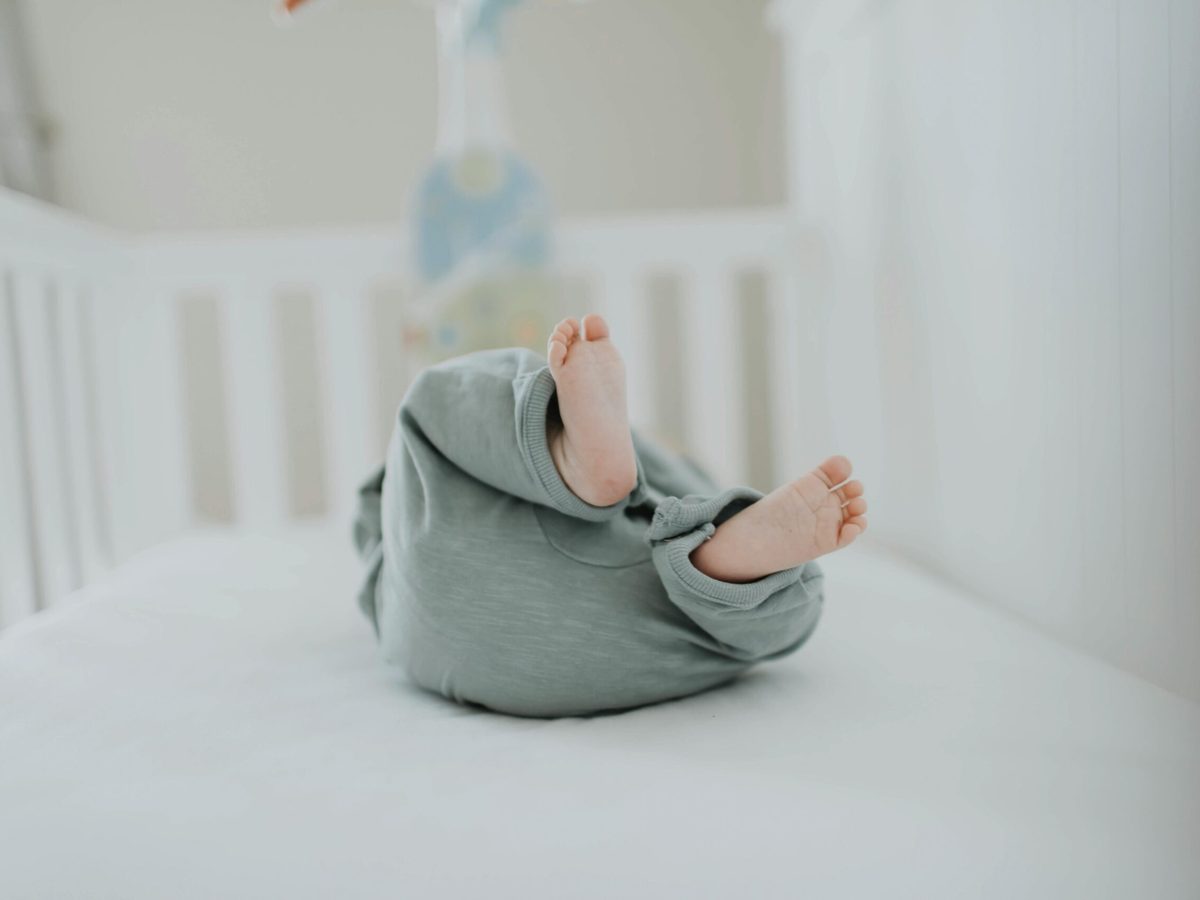 Baby in een ledikant met alleen een strak hoeslaken